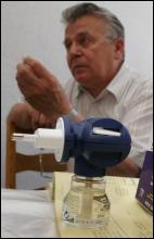 Сергій Світлий показує пластину, що вставляють у пристрій фумігатор (на передньому плані), і яка випаровує отруту від комарів