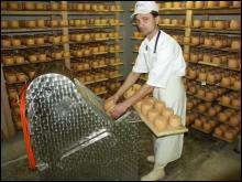 Работник сыроварни Иван Пригара на специальной протирочной машине счищает плесень с головок сыра ”Селесский”