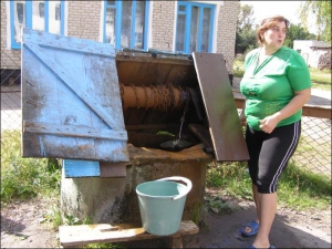 Вихователька дитсадка Тетяна Коваль дістає привізну воду з резервуару-криниці в селі Пугач Сарненського району на Рівненщині