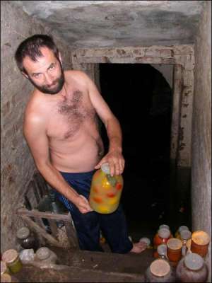 Житель села Хуторы Черкасского района Олег Титов выносит из затопленного погреба домашние консервы