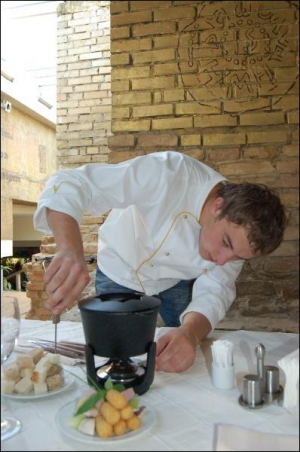 Шеф-повар киевского ”Фондю-бара” Александр Ворона показывает, как правильно накалывать и макать сухари в фондю
