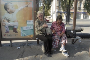 Жебрачки Галина Голубєва та Надя відпочивають на трамвайній зупинці неподалік Житнього ринку в Києві
