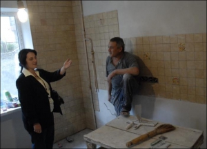 Киянка Юлія Жук показує вже оновлену кухню. Майстрові Миколі Брижатюку (праворуч) ”старі” кахлі довелося зняти і покласти заново