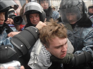 Офицеры ”Беркута” задерживают 17-летнего Андрея Лозового — активиста партии ”Братство” за то, что он бросил дымовую шашку перед демонстрантами из Коммунистической партии