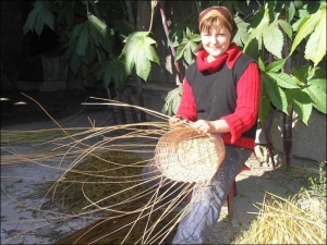 Олена Ярмакович на своєму подвір’ї в селі Іза Хустського району Закарпатської області плете з лози кошик для квітів
