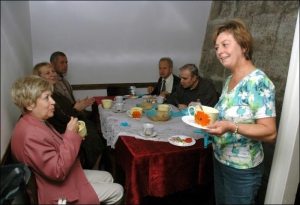 Польский врач Анна Суховецка (справа) подает ужин группе ”оптимальщиков” во львовском кафе ”Цветы на руинах”