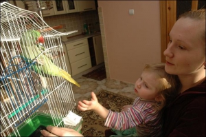 Жительница села Муроване, что около Львова, Оля Купецкая с двухлетней дочкой Анночкой угощают Гошу кормом для больших попугаев. Птицу подарил семье дед Ольги Богдан