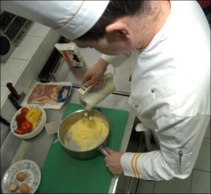 Шеф-повар ресторана ”Царское Село” Андрей Валенчук звбивает яйца с молоком и мукой для омлета с овощами