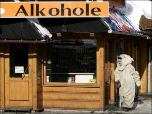 Турист в костюме белого медведя выходит из магазина спиртных напитков в центре курортного местечка Закопане в польских Татрах