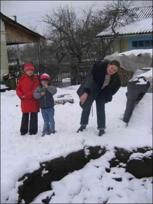 Віра Паранчук (праворуч) із селища Шкло Яворівського району на Львівщині показує яму, що утворилася біля її хати. Доки не випав сніг, провалля щодня збільшувалося на півметра