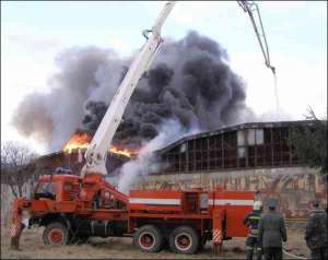 В прикарпатском городе Калуше гасят пожар на складе обоев. КамАЗ, оборудованный стрелой длиною несколько десятков метров, сверху льет воду на пылающие помещения