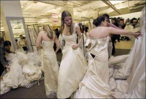 Молодые американки примеряют свадебные платья в магазине ”Филен” в Нью-Йорке. Больше тысячи дизайнерских моделей там выставила по цене 249 долларов