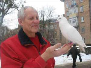 Петро Пінчук з білим спортивним голубом біля голубника, який він спорудив на подвір’ї свого будинку, що неподалік від центру Луцька