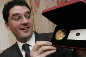 Филипп Штайдл, представитель немецкой компании ”Шелер-Мюнцгандел”, показывает украшенную кристаллами золотую монету ”Снежинка” из собственной коллекции