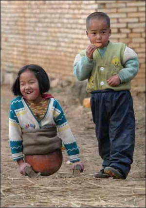 10-летняя Цянь Хунянь играется с другом на улице в городе Цюйцзин китайской провинции Юньнань. В три года девочка попала под колеса грузовика и потеряла нижнюю часть тела. С тех пор ногами ей служили баскетбольные мячи