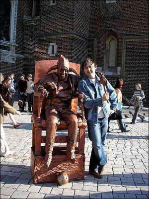 Турист фотографируется на краковском рынке с уличным мимом. Актер-памятник изображает шута из картины польского художника Яна Матейка ”Станьчик”