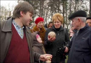 Жінка роздивляється страусину писанку, яку львів’янин Олег Семчишин (ліворуч) купив на аукціоні в ”Шевченківському гаю” за 95 гривень