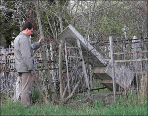 Житель Николаева рассматривает могилы на городском кладбище. Вандалы попереворачивали памятники и позабирали все ценные вещи