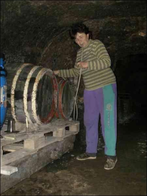 Жительница села Нижнее Солотвино Любовь Фешко в своем погребе в известняке тянет из бочки вино