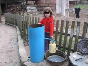 П’ятирічна Вікторія Ісакова набирає воду з колонки біля батьківського двору в селищі Понорниця Коропського району Чернігівської області. Батьки забороняють дитині відходити далеко від хати