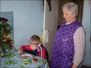 Владимир Ветошко ест помидорный суп у себя дома в городе Городок Львовской области. Над ним стоит бабушка Екатерина Ивановна