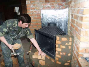 Дмитро Тишковський обкладає цеглою чавунну камеру згоряння каміна у вінницькій новобудові