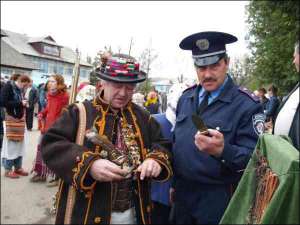 На фестивале ”Этноэволюция” Роман Стринадюк (слева) показывает нож и пистолет майору местной милиции
