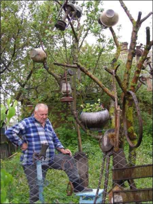 Колишній шофер із села Бокійма Млинівського району Рівненської області Леонід Гурій біля свого дерева, обвішаного старовинними речами