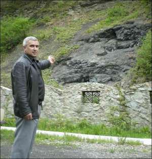 Предприниматель из закарпатского села Тячевские Лазы Юрий Ключкей показывает скалу, под которой формируется черная вода