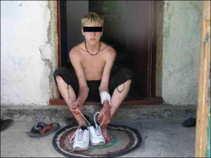 Житель міста Берислав на Херсонщині Михайло Тищенко взуває кросівки, щоб їхати з міліцією. На ногах хлопця видно засохлу кров — за годину до цього він зарубав трьох людей