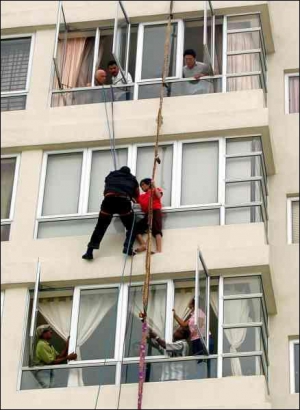 Малазійські рятувальники знімають з 12-го поверху багатоповерхівки  індонезійку Шамелін. Жінка працювала домогосподаркою у заможній родині. Однак утекла, бо господиня била її, морила голодом і не випускала з квартири