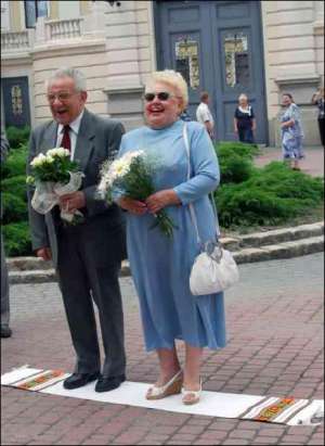 Через 50 років після весілля Ірина та Роман Чайківські стоять на рушнику біля колишнього палацу урочистих подій у Львові