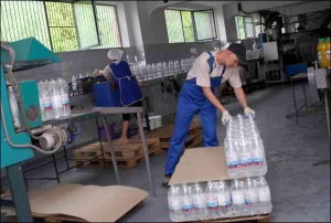 Пакувальник складає на піддон пляшки мінеральної води ”Гірська кришталева” в цеху розливу підприємства ”Віктар”