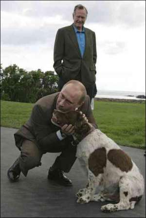 Прибыв в поместье американского президента Джорджа Буша, российский руководитель Владимир Путин поздоровался с его собакой. На заднем плане стоит Джордж Буш-старший