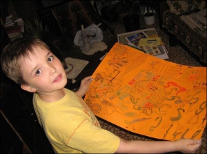 Костя Сапун показывает свой рисунок ”Цифроцветок”. Мальчик выполнил его в оранжевых тонах