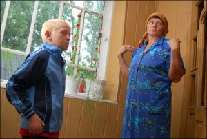 Оксана Единак и ее сын Иосиф стоят у окна дома в Мишлятичах Мостисского района Львовской области, из которого 13 лет тому назад выпали две дочки-близнецы. В апреле на одном из оконных стекол появилось изображение Богородицы