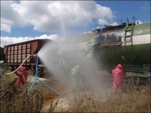 Працівники загону МНС поливають цистерну водою, щоб охолодити соляну кислоту і зменшити її випаровування