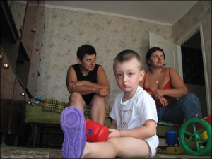 Тернопольчанин Толик Попов играется в комнате бабушки. На диване сидят его бабушка Людмила (слева) и мама Таня
