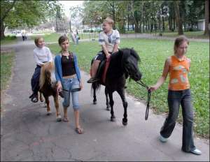 Марк Пилипенко й Альона Воскобой катаються на поні у столичному парку ”Нивки”