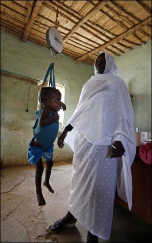 Медсестра взвешивает ребенка в рамках одной из немногочисленных медицинских программ в суданском лагере беженцев Майо