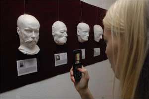 Відвідувачка Музею одної вулиці фотографує на мобільний телефон посмертну маску французького поета Поля Верлена. В короткій біографії під маскою написано: ”Поль Верлен вел распутный гомосексуальный образ жизни”