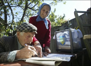 Жінка допомагає своєму чоловікові заповнити бюлетень на парламентських виборах у селі Личанка, що на Київщині, 30 вересня 2007 року