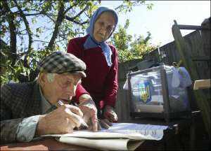 Женщина помогает своему мужу заполнить бюллетень на парламентских выборах в селе Личанка, на Киевщине, 30 сентября 2007 года