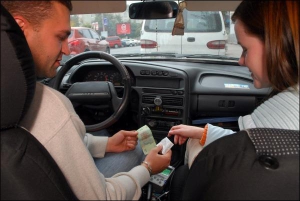 Водій таксі, обладнаного таксометром, 29-річний Ярослав Кіт дає чек пасажирці Ірині Рожок
