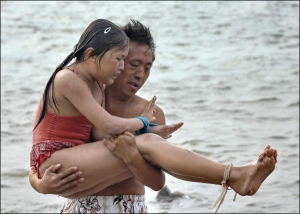 Хуан Даошен достает дочку из воды после того, как она проплыла три километра со связанными руками и ногами. Таким образом отец готовит девочку к Олимпийским играм 