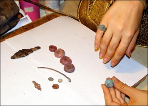 На столе в лаборатории Центра охраны и изучения памяток археологии лежат серебряные монеты, пряслица для веретена, обломок шейной гривни, наконечник стрелы. На руке — бронзовый перстень. В другой — пуговица. Все это нашли в Полтаве в руинах глиняных домов