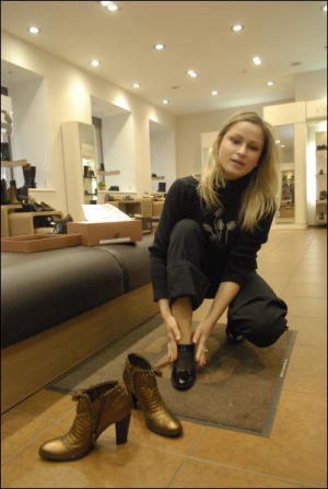 В магазине ”Эконика”, на столичной ул. Артема, киевлянка Ольга Пышная примеряет черные ботильоны за 916 гривен. Стоящие рядом золотистые ботинки продаются за 1468 гривен