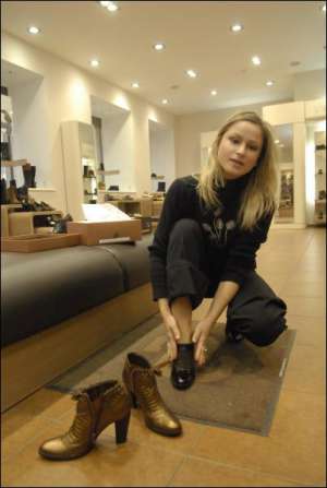 В магазине ”Эконика”, на столичной ул. Артема, киевлянка Ольга Пышная примеряет черные ботильоны за 916 гривен. Стоящие рядом золотистые ботинки продаются за 1468 гривен