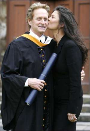 Актер Майкл Дуглас получает почетное звание доктора права в университете Сент Эндрюс в Шотландии. Жена Кэтрин Зета-Джонс поздравляет его. 21 июня 2006