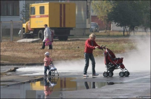 Жителька Дарниці з дитиною переходять вулицю Ревуцького, яку 17 жовтня 2007 року затопило гарячою водою із тріснутої труби теплопостачання